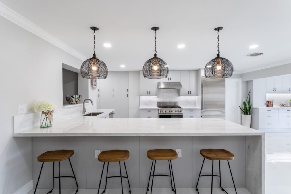 Modern kitchen with island, stools, and pendant lights.