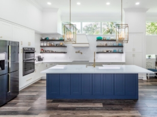 Modern kitchen with blue island and white cabinets.