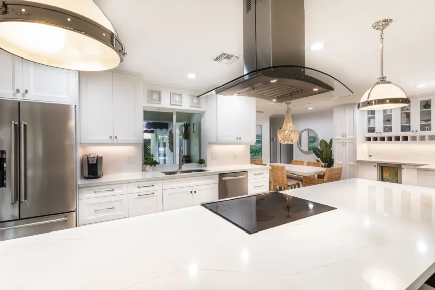 Bright kitchen with a white quartz island, cooktop and stainless island hood