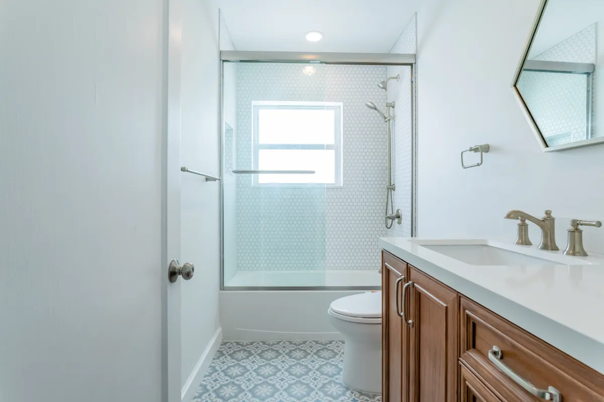 Bathroom with wood vanity, glass shower and patterned tile floor