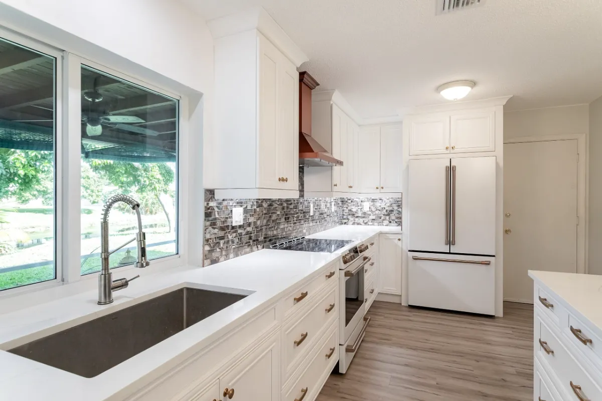 White kitchen with undermount sink, mosaic backsplash and copper hood